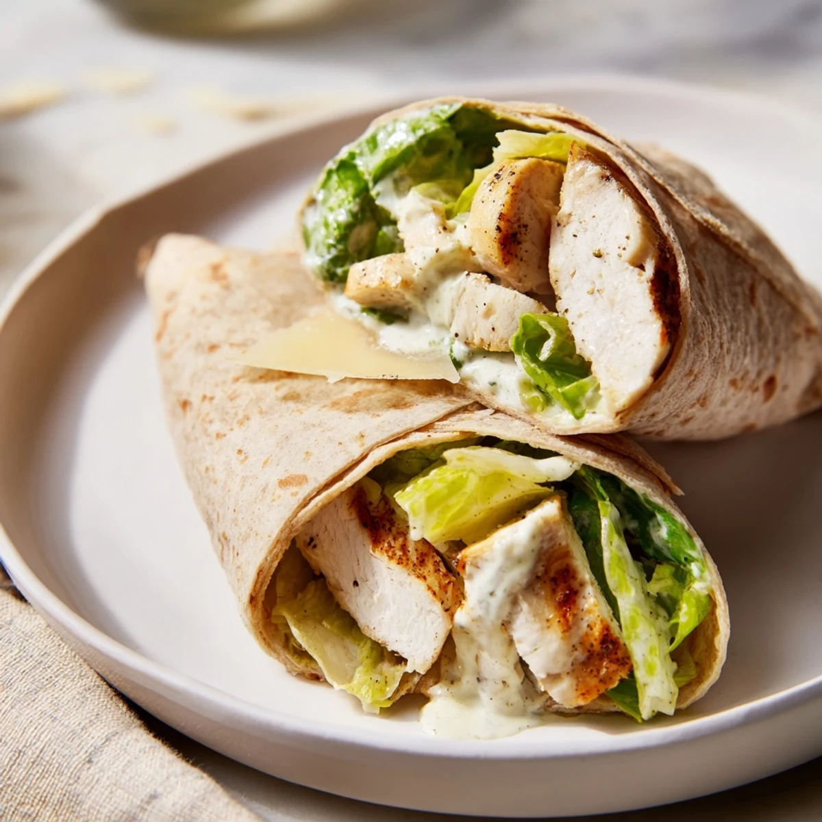 Close-up of a perfectly rolled Chicken Caesar Wrap, showing the textures of fresh ingredients inside.