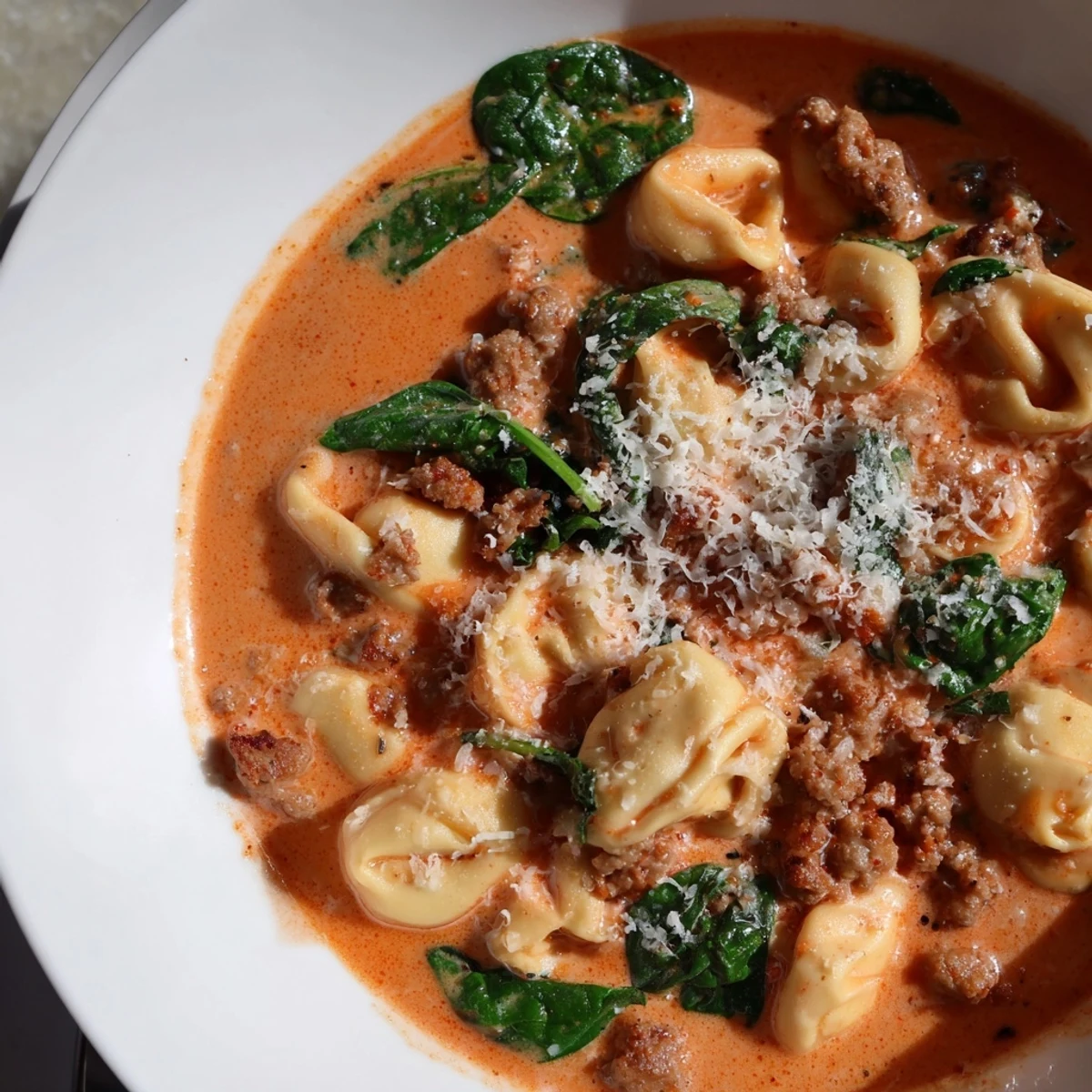 Steaming Tuscan Tortellini Soup featuring cheesy tortellini, rich tomato cream broth, and fresh basil garnish.