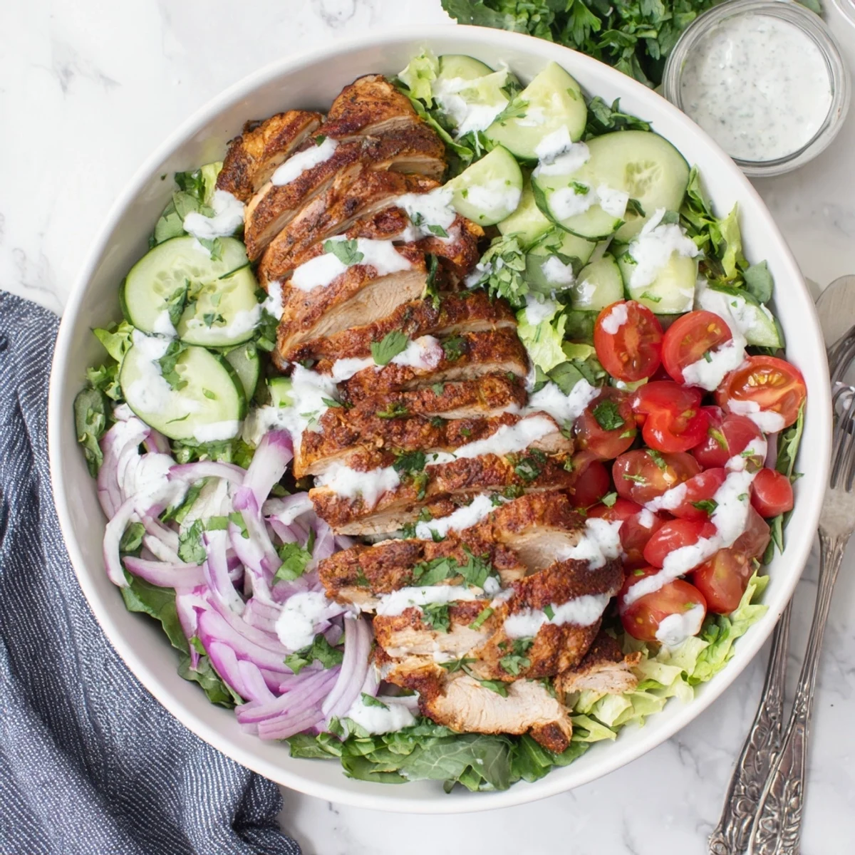 Juicy, spiced Chicken Shawarma Salad Bowl piled high with crisp greens, cherry tomatoes, cucumbers, and a creamy garlic drizzle.  