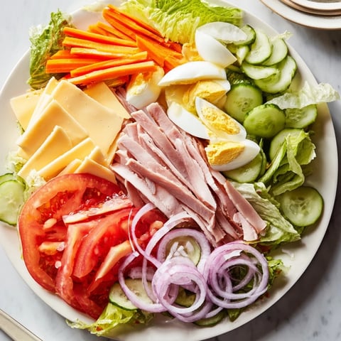 A vibrant Chef Salad with layers of ham, cheese, and fresh veggies, ready to enjoy.