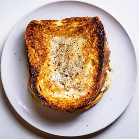Golden, crispy sourdough slices stuffed with melted Gruyère cheese and drizzled with aromatic truffle oil for a gourmet grilled cheese experience.  