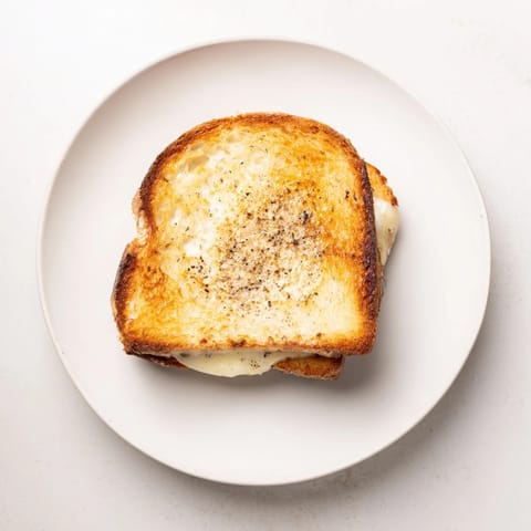 A decadent Truffle Grilled Cheese sandwich rests on a rustic cutting board, showcasing its melty interior and perfectly toasted, buttery crust.  