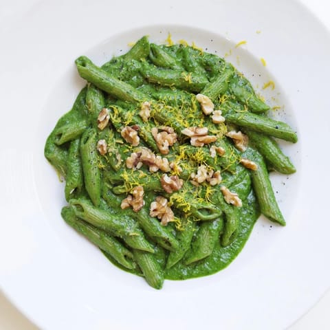 Freshly blended spinach walnut sauce coats every strand of al dente pasta, creating a vibrant green, plant-based main dish.  