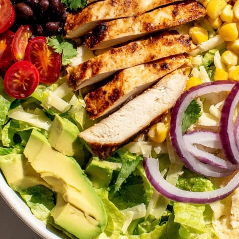Colorful Honey Lime Chicken Taco Salad features diced avocado, cherry tomatoes, and crunchy tortilla strips for a satisfying, zesty meal.  