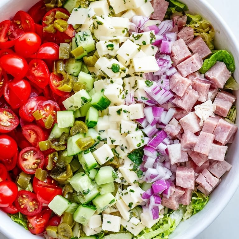 Colorful Italian Deli Chopped Chicken Salad featuring cherry tomatoes, pepperoncini, red onion, and cucumber on a bed of fresh greens.