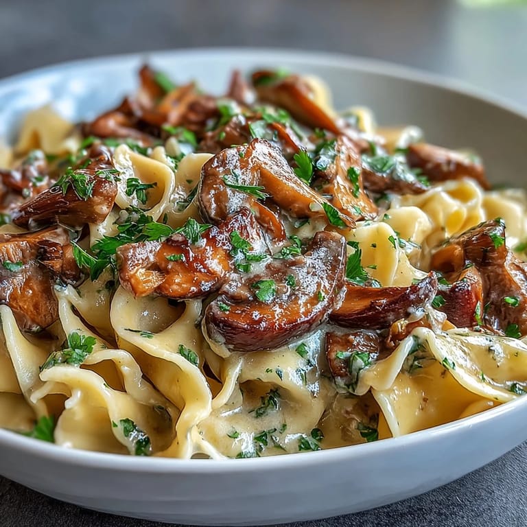 Close-up view of a plate of mushroom stroganoff, showcasing tender egg noodles coated in a velvety, umami-rich sauce.